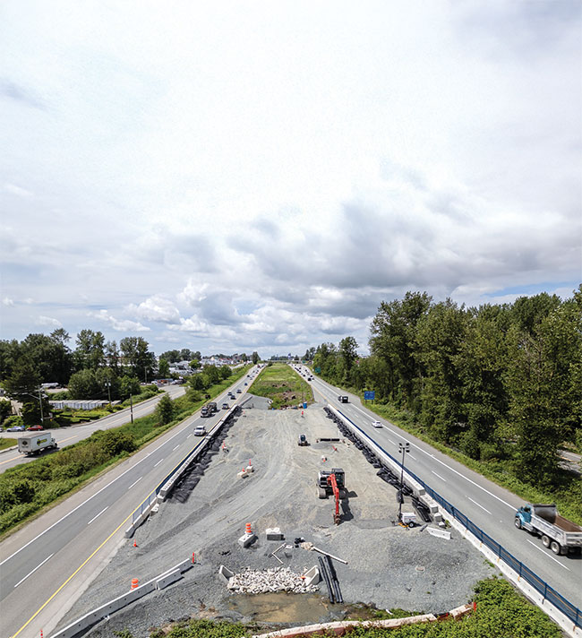 Aerial view of highway construction with equipment and traffic on adjacent lanes